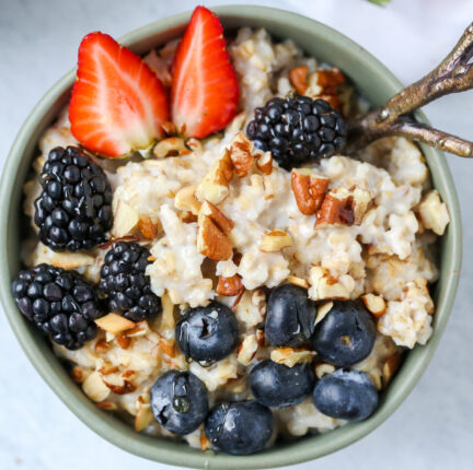 A bowl of oatmeal with blueberries, blackberries, strawberries and nuts
