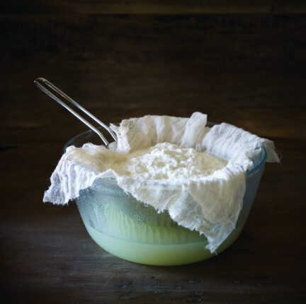 Making ricotta cheese on a dark wooden surface