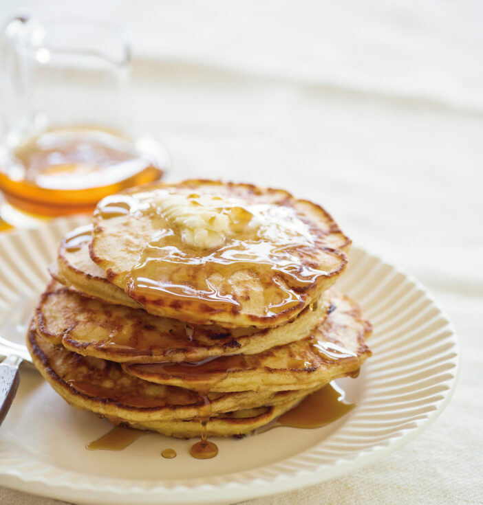 Syrup covered pancakes on a white plate