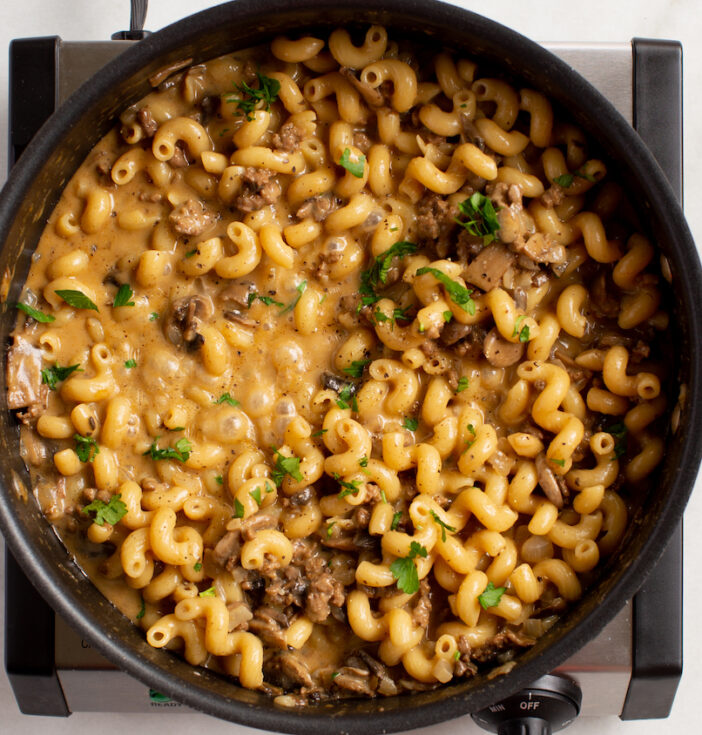A skillet of cheesy pasta on a single burner