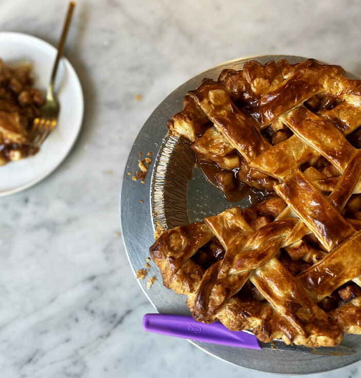 Photo of a apple pie with a slice cut out and placed on a nearby plate